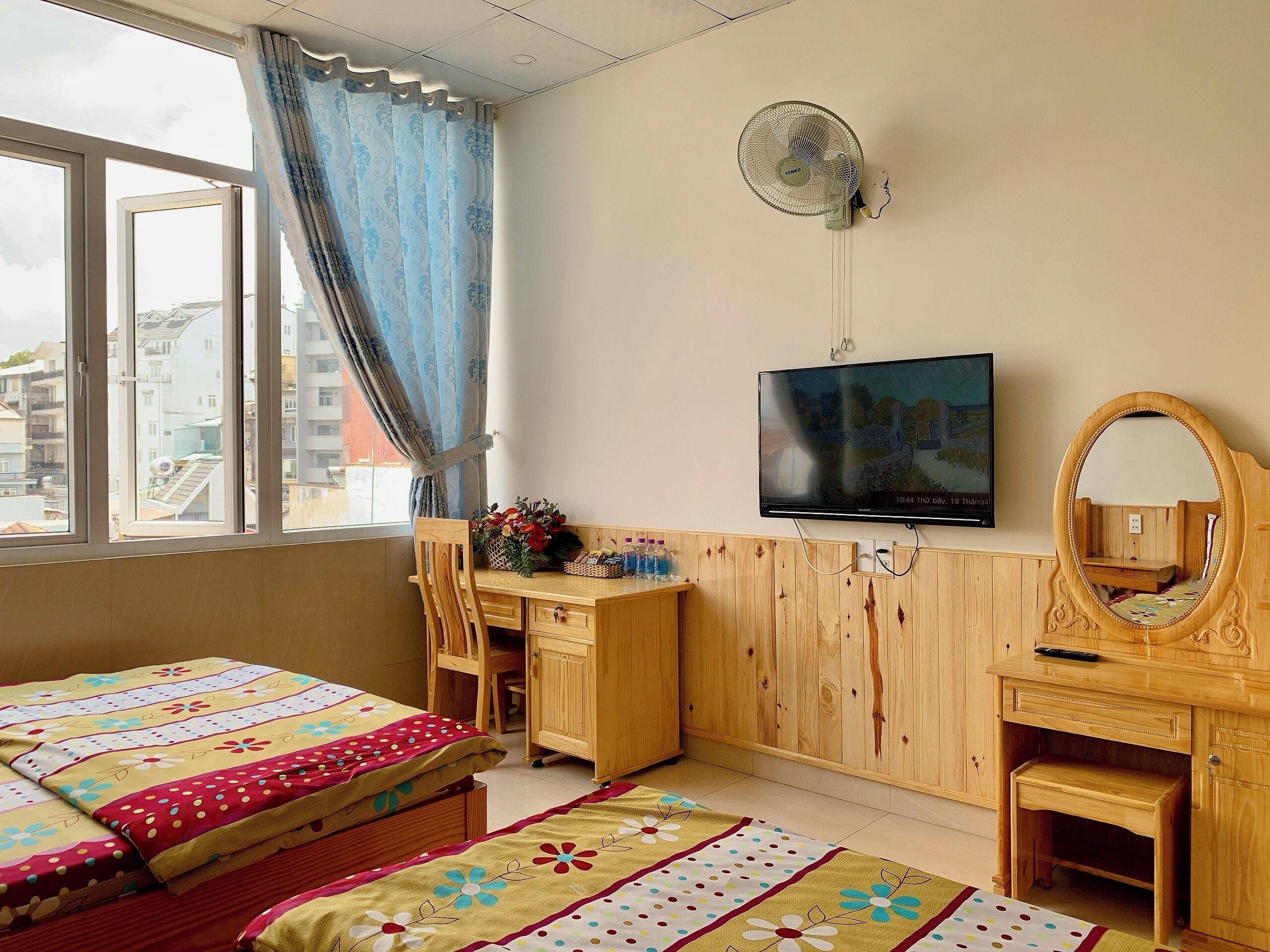 Un dormitorio con cama, escritorio, silla, televisor y espejo.