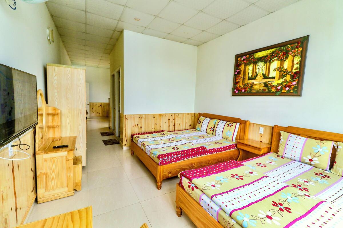 A room with two wooden beds, a TV, and a wooden cabinet.