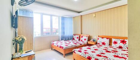 A bedroom with two wooden beds, a desk with a lamp, and a window with curtains.