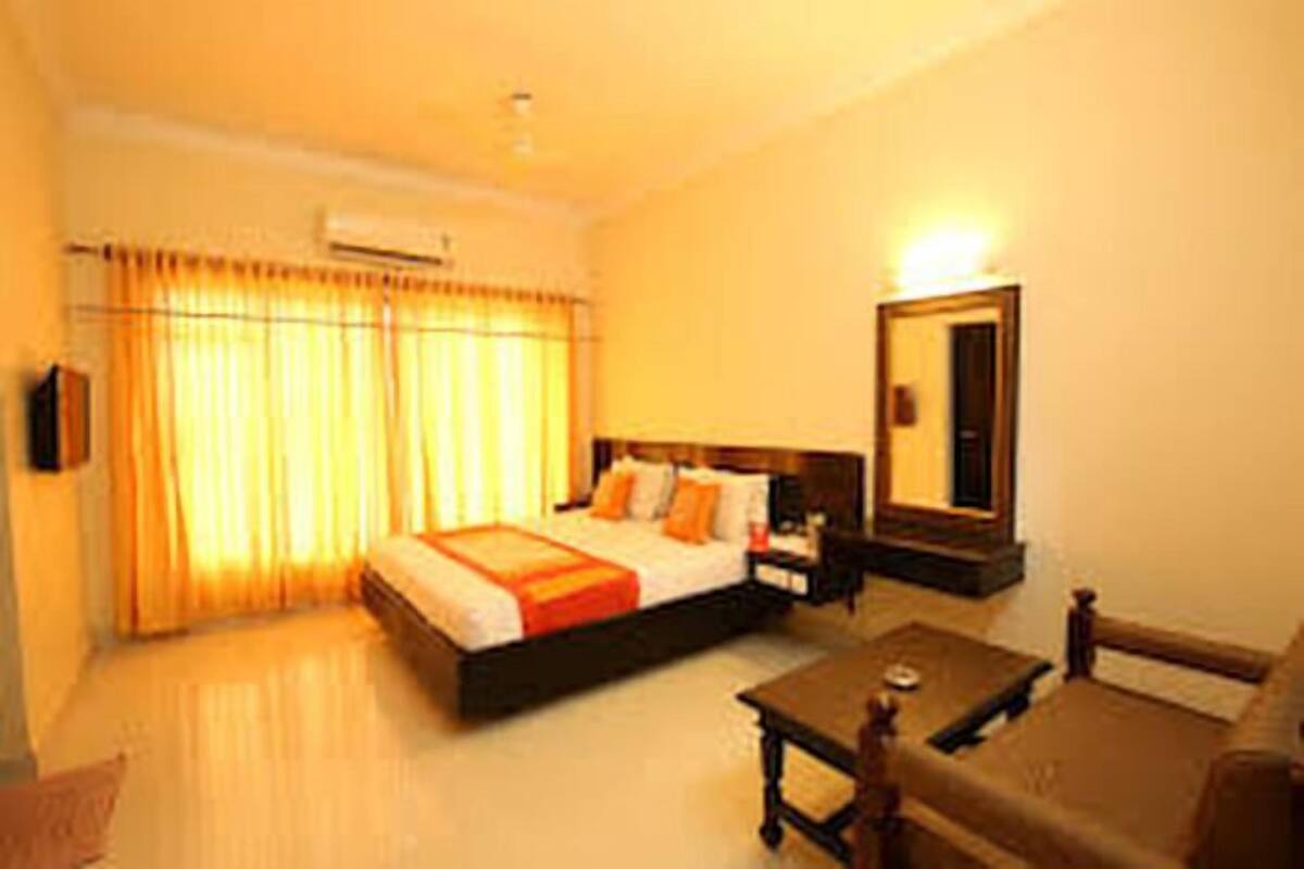 A hotel room with a bed, a nightstand, a mirror, a sofa, and a coffee table.
