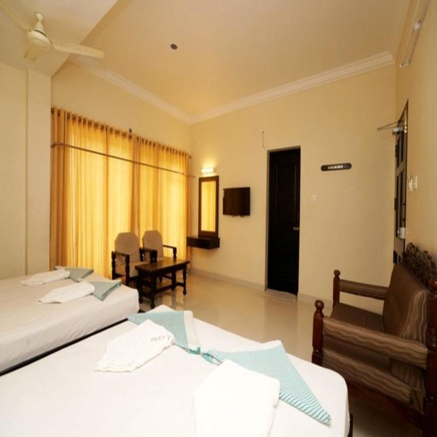 A hotel room with two beds, a desk, a chair, and a television.