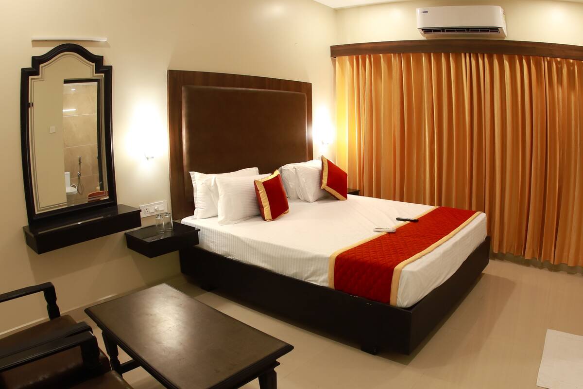 A hotel room with a large bed, bedside tables, a mirror, and a window with curtains.