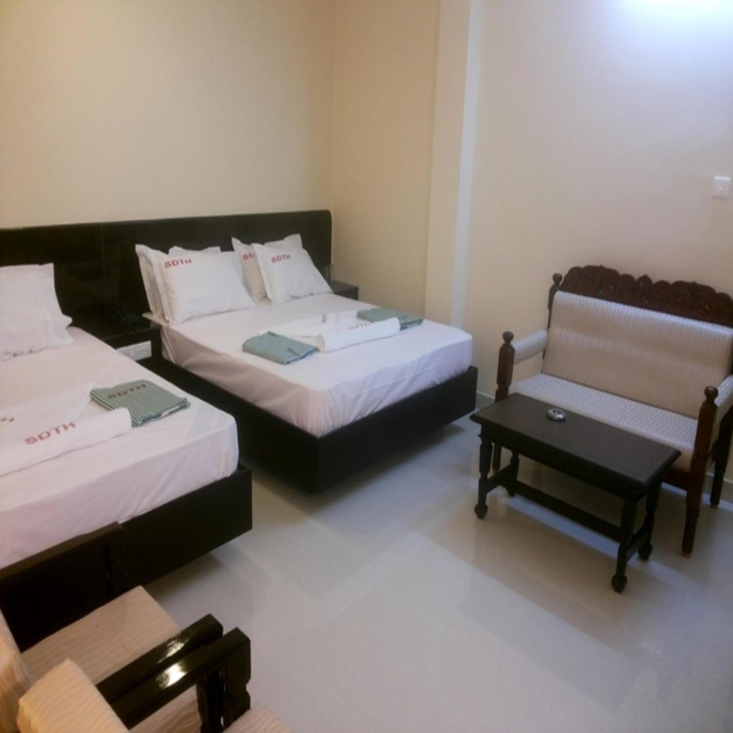 A hotel room with two beds, a sofa, and a small table.