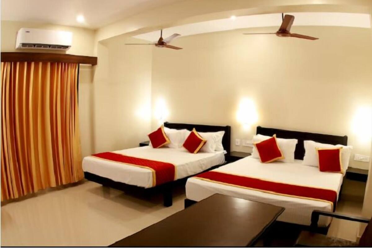 A hotel room with two beds, a ceiling fan, an air conditioning unit, and a curtain.