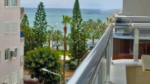 Ein Balkon mit Blick auf das Meer, umgeben von Grünflächen und Gebäuden.