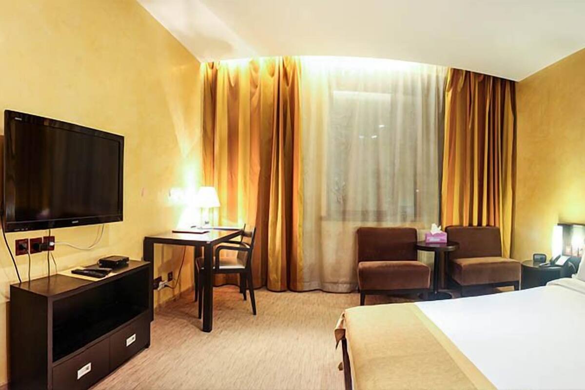 Una habitación de hotel con cama, televisión, escritorio con silla y sofá.