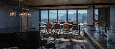 Una sala de conferencias moderna con un piano, ventanas amplias y una zona de bar.
