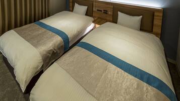 A hotel room with two beds, each with a headboard and a bedside table.