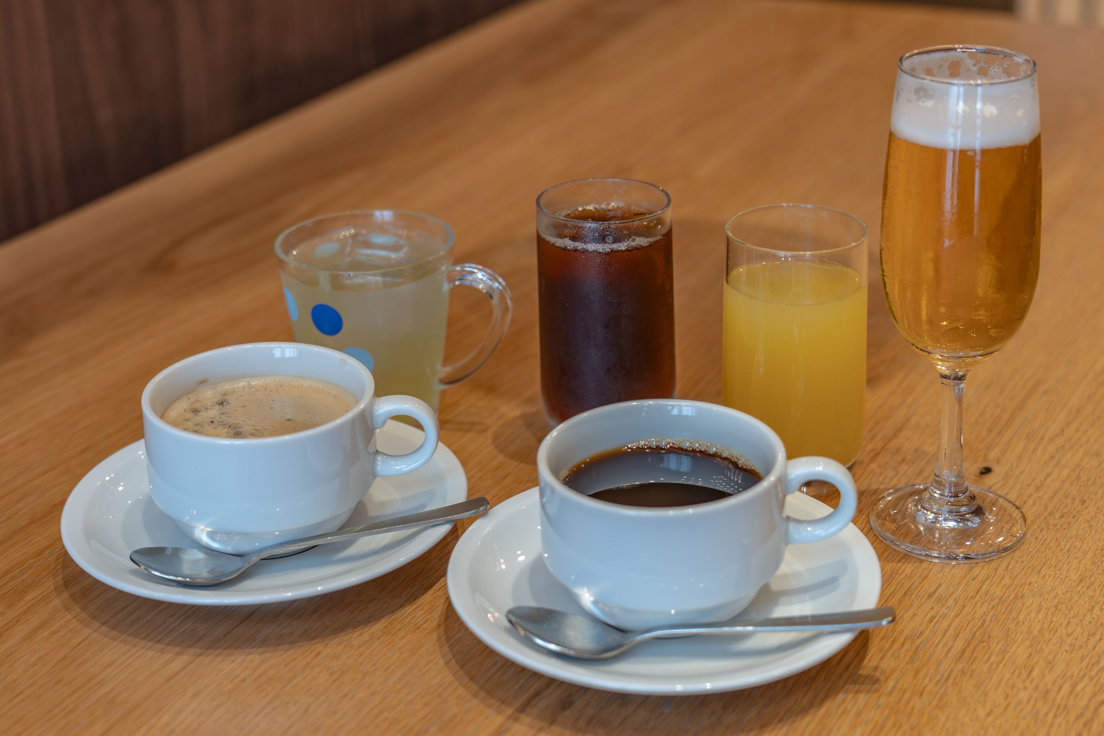 A table with four cups of beverages and a wine glass.