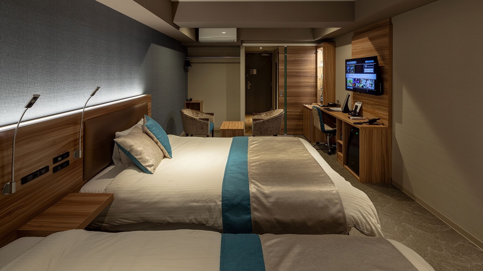 A hotel room with a bed, bedside tables, a desk, a TV, and a chair.