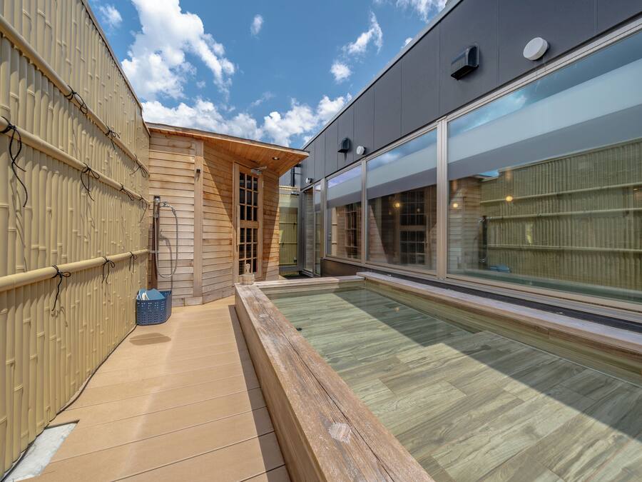 A modern pool area with a wooden deck, a glass enclosure, and a metal fence.