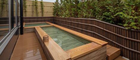 A wooden deck with a hot tub and a wooden bench.