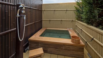 A hot tub with a wooden frame, a wooden bench, and a wooden bucket.