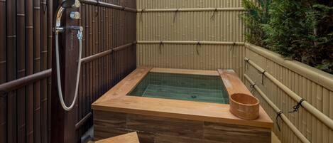 Un jacuzzi con estructura de madera, un banco de madera y un cubo de madera.
