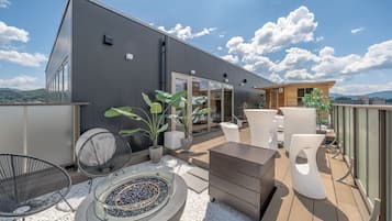 A modern outdoor patio with seating, a fire pit, and potted plants.
