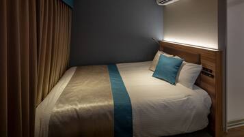 Habitación de hotel con una cama grande, cabecera con controles, aire acondicionado de pared y una cortina a la izquierda.