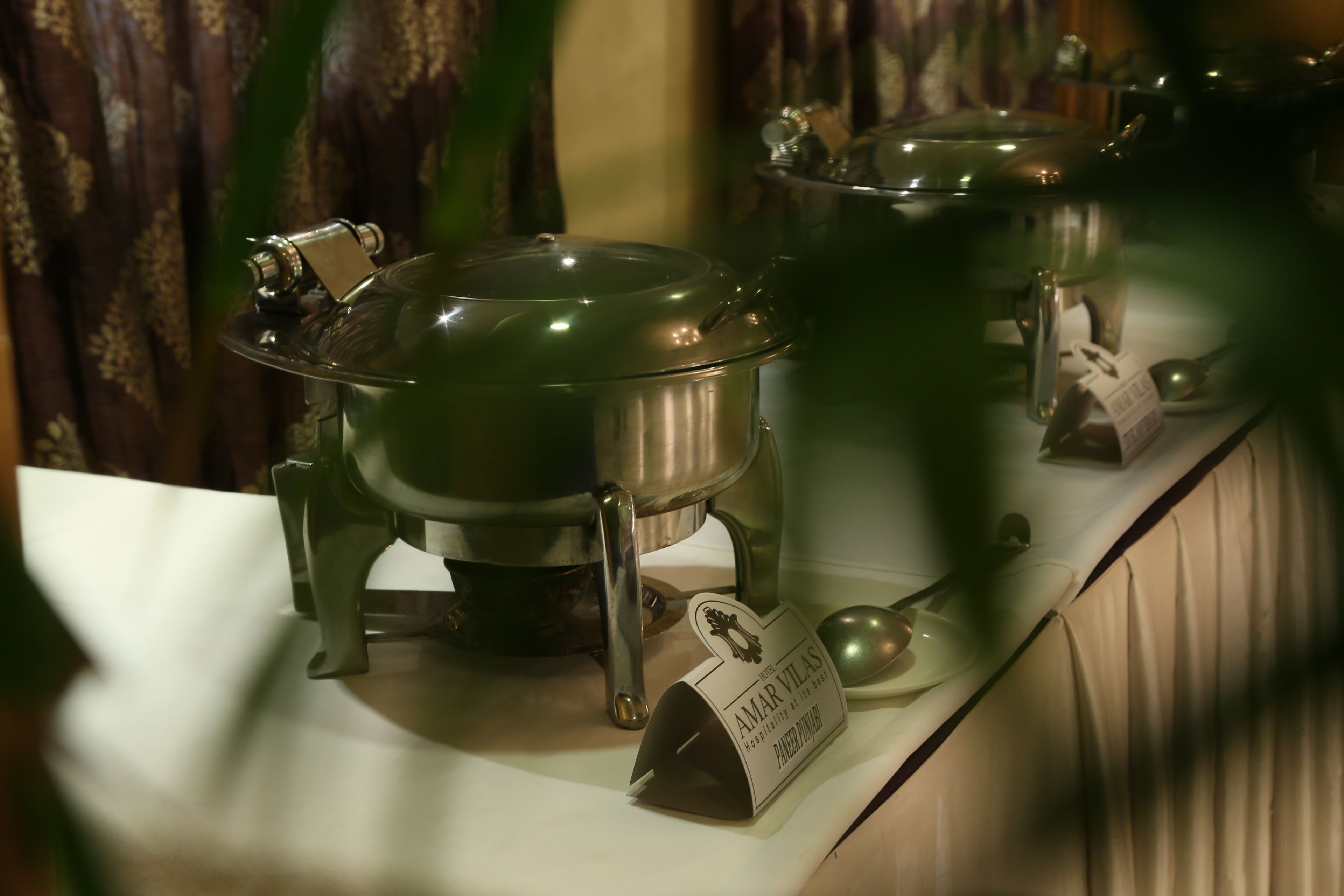 Groene keramieken potten op een tafel, met een bord waarop 'AMAR VILAS' staat.