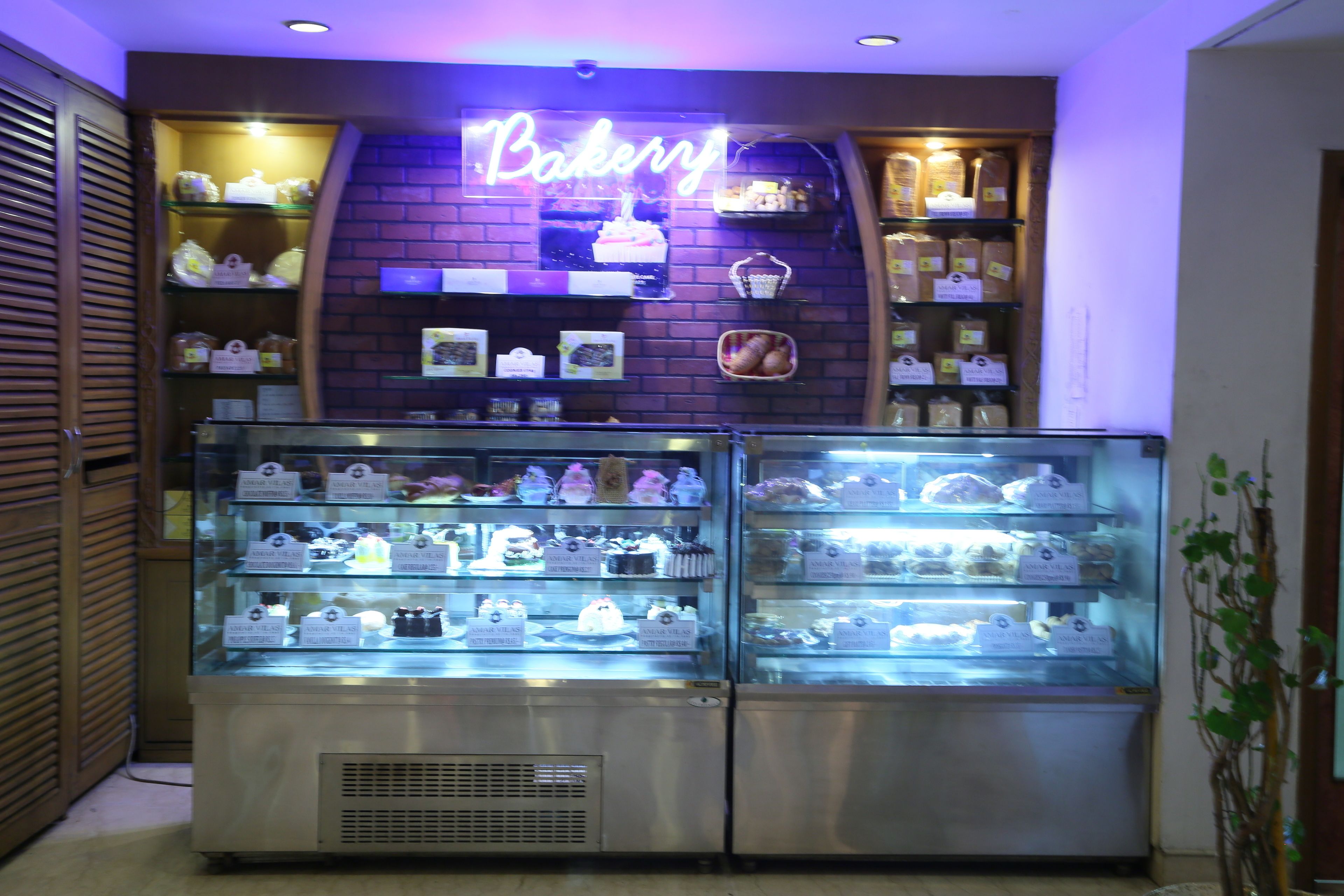 A bakery display case with various baked goods and a neon sign that reads "Bakery".