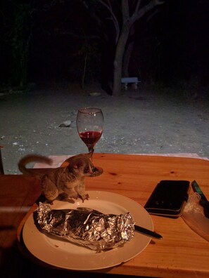 A table with a plate of foil-wrapped food, a wine glass, and a smartphone. - Rafiki's Resthouse (Nkomazi)