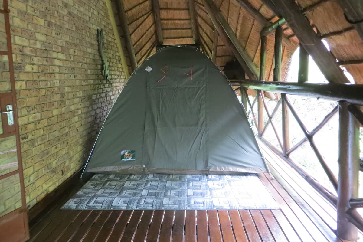 A tent set up inside a room with brick walls and a wooden floor.