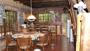 Un comedor rústico con mobiliario de madera, pared de ladrillo y un ventanal grande.