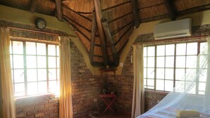 Una habitación con cama, pared de ladrillo, ventana y ventilador de techo.