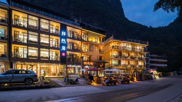 A multi-story hotel with balconies and a mountain backdrop. - CTN LiRiver Boutique Hotel (Guilin)