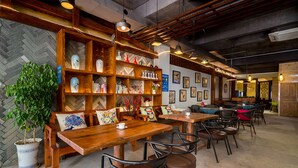 A cozy cafe with wooden furniture, a bookshelf, and a potted plant. - CTN LiRiver Boutique Hotel (Guilin)
