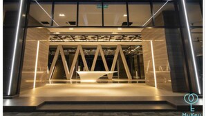 Eine moderne Hotelhalle mit einer geometrischen Lichtinstallation und einer zentralen Sitzgruppe.