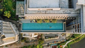 Eine Vogelperspektive auf ein Gebäude mit Pool auf dem Dach, umgeben von viel Grün und an einer Straße gelegen.