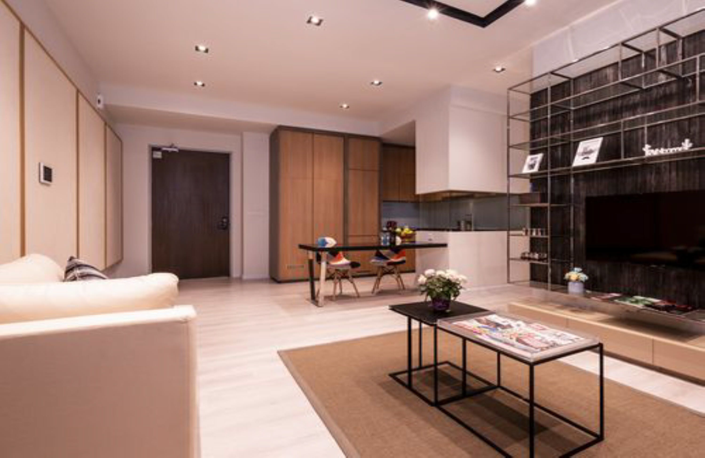 Een moderne woonkamer met een bank, een salontafel en een open haard. Er is een keuken met houten kastjes en een eettafel.
