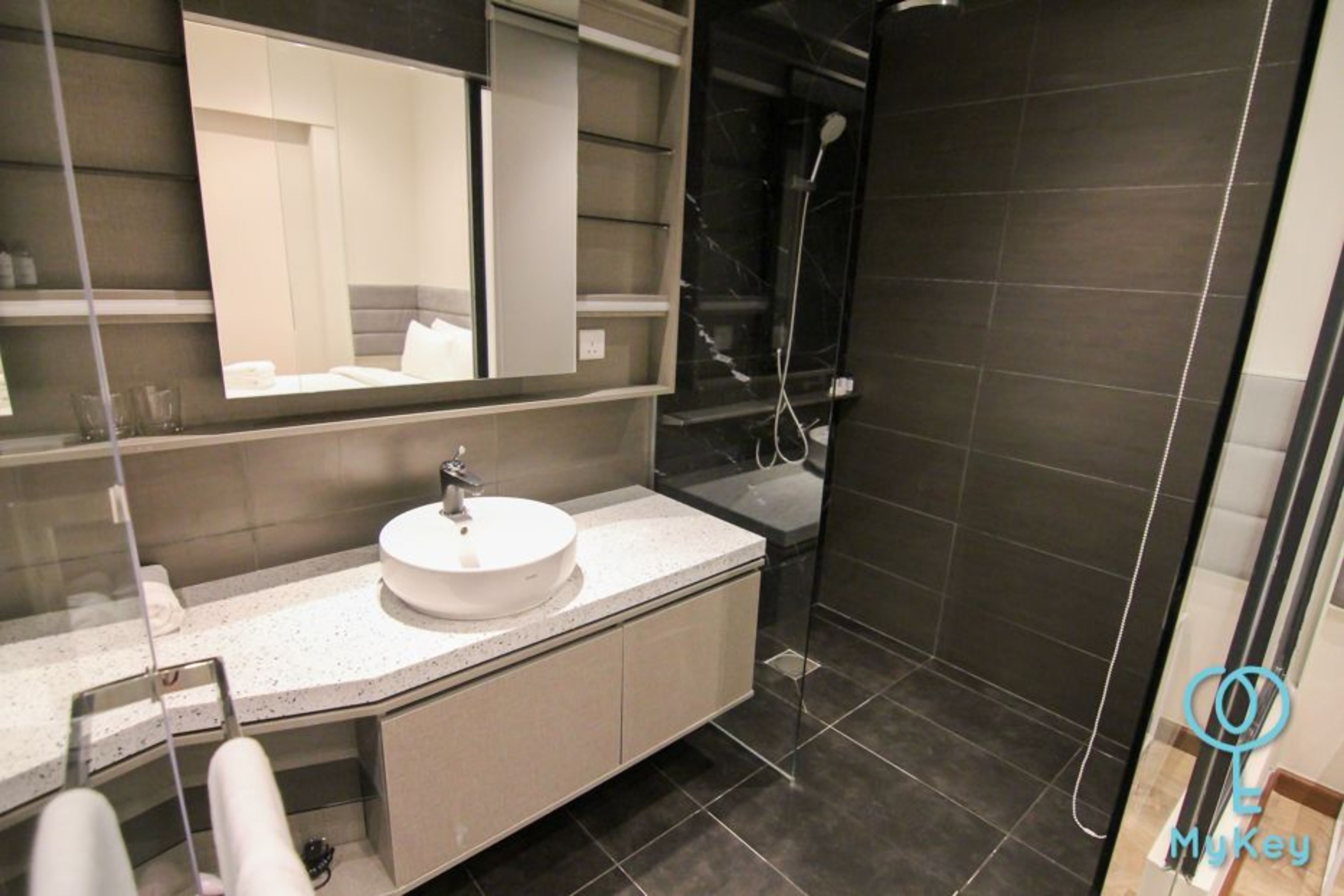 A modern bathroom with a round sink, a large mirror, and a shower area.