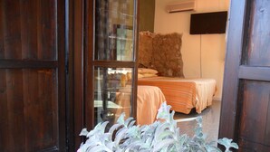 Una habitación con cama, televisor en la pared y ventana con vistas al exterior.