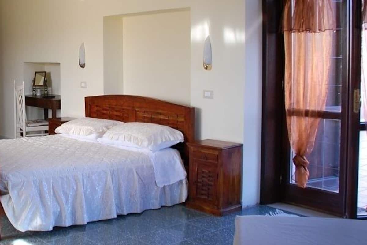 A bedroom with a wooden bed, a nightstand, a chair, and a wardrobe.