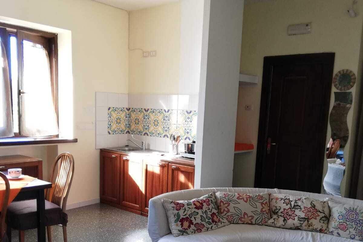 A compact living space with a dining area, kitchenette, and a sofa with floral cushions.
