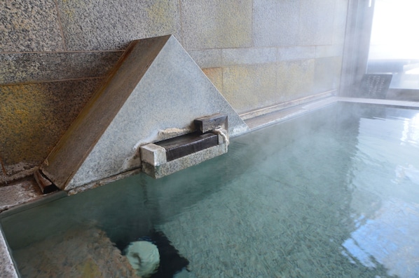 Une piscine en pierre, dotée d’une structure en bois et d’une corde.