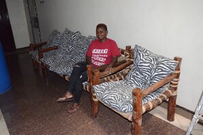 A person sitting on a zebra-patterned sofa in a room with a tiled floor and a plain wall.