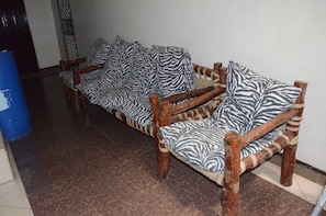Eine Reihe von Holzdavätzen mit Zebra-Muster Kissen, angeordnet in einer Diele mit Fliesenboden.
