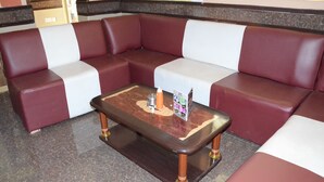 A seating area with a wooden coffee table, cushioned benches, and a tiled floor. - Sir Kanja's Hotel (Nairobi)