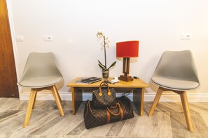 A room with two chairs, a table, a lamp, a plant, and a bag. - Eccelso Hotel (Rome)