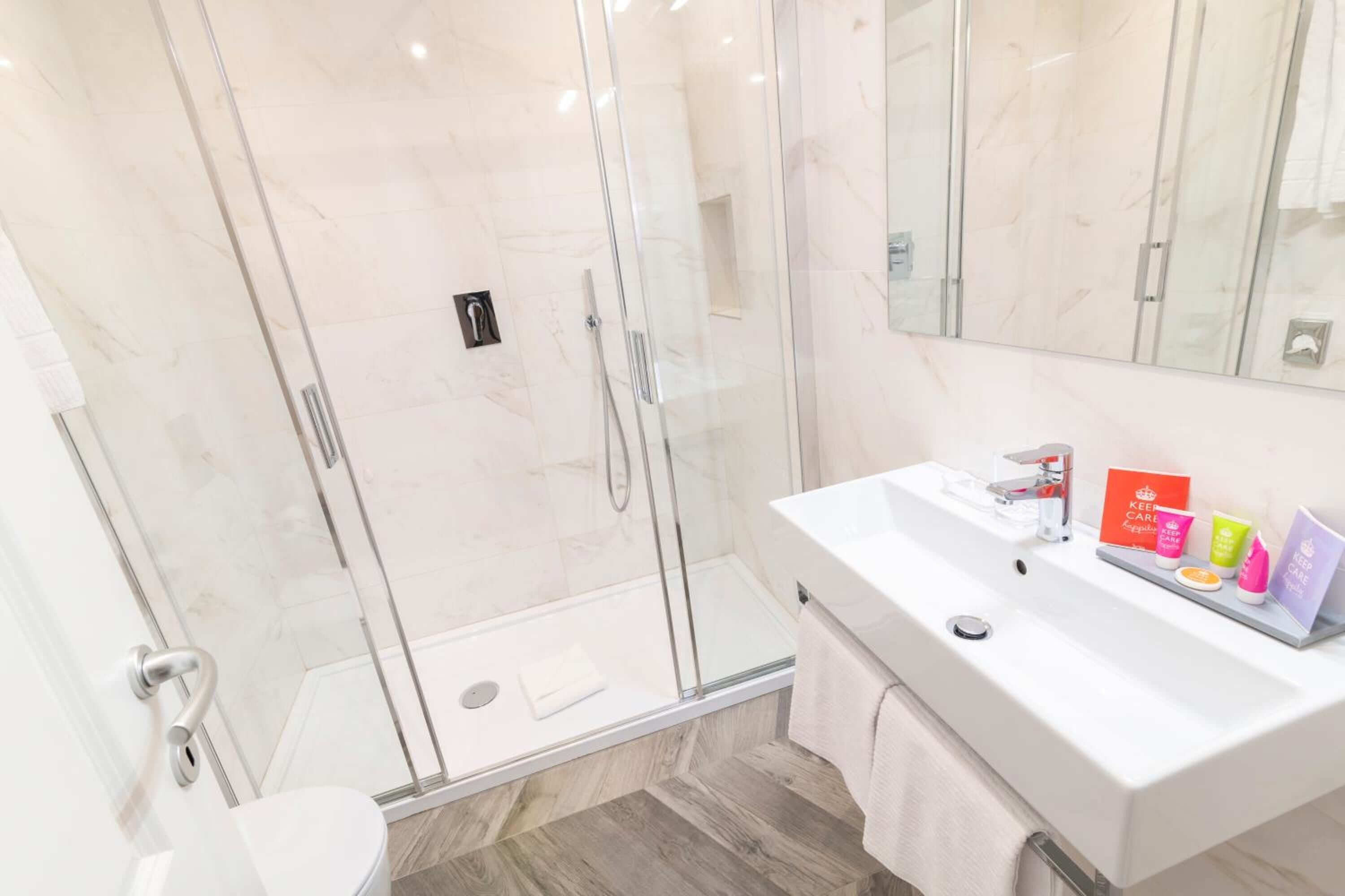 A modern bathroom with a glass-enclosed shower, a white sink, and a mirror above it.