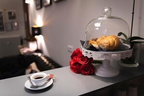 A table with a pastry under a glass dome, a cup of coffee, and a bouquet of red roses. - Eccelso Hotel (Rome)