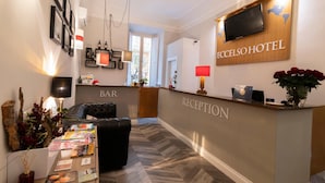 Uma área de recepção de hotel com piso em padrão herringbone, um bar e um balcão de atendimento.