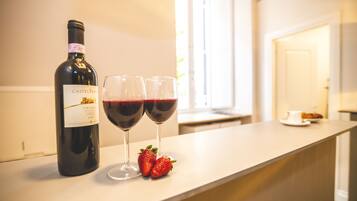 Uma garrafa de vinho Château Mouton Rothschild, duas taças de vinho tinto e duas morangos em uma bancada de cozinha.