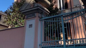 Um edifício histórico com fachada rosa, detalhes arquitetônicos elaborados e entrada protegida por grades.