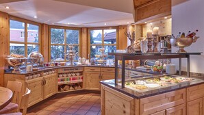 Interior de madera con un bufé de desayuno, variedad de tés y vistas al exterior.