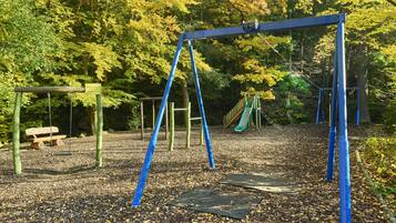 Un parque infantil con columpios, un tobogán y un banco.