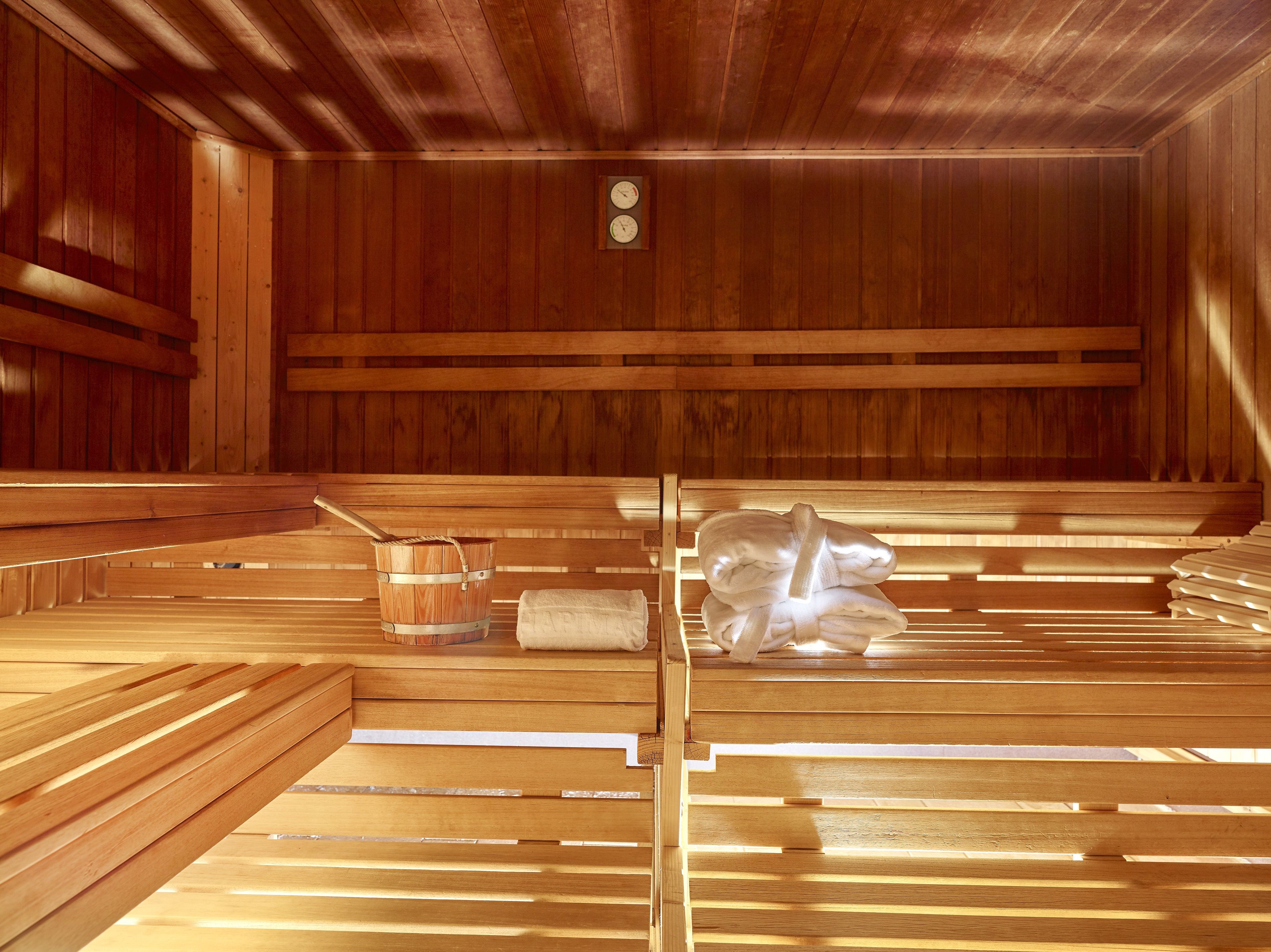 A sauna with wooden benches, a wooden bucket, and towels.