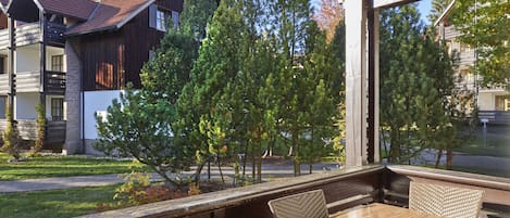 Un balcón con mesa y sillas, con vista a una zona residencial con casas y árboles.