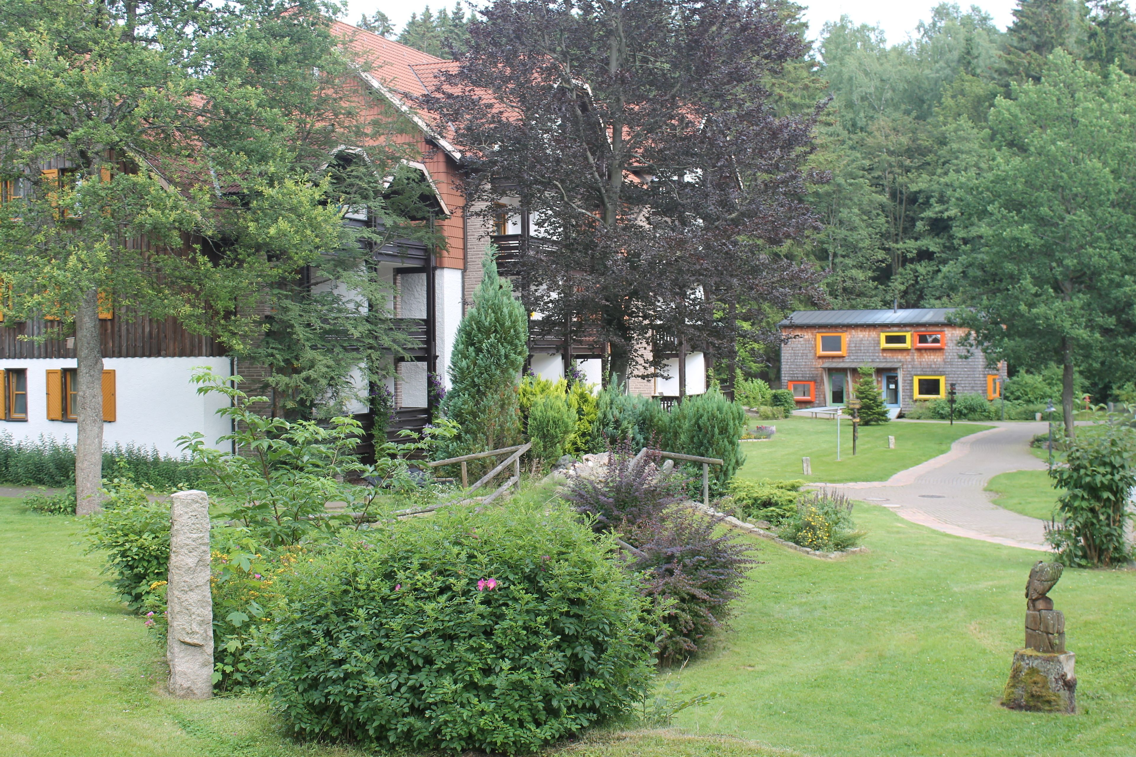 A traditional house with a garden, a stone pathway, and a wooden fence.